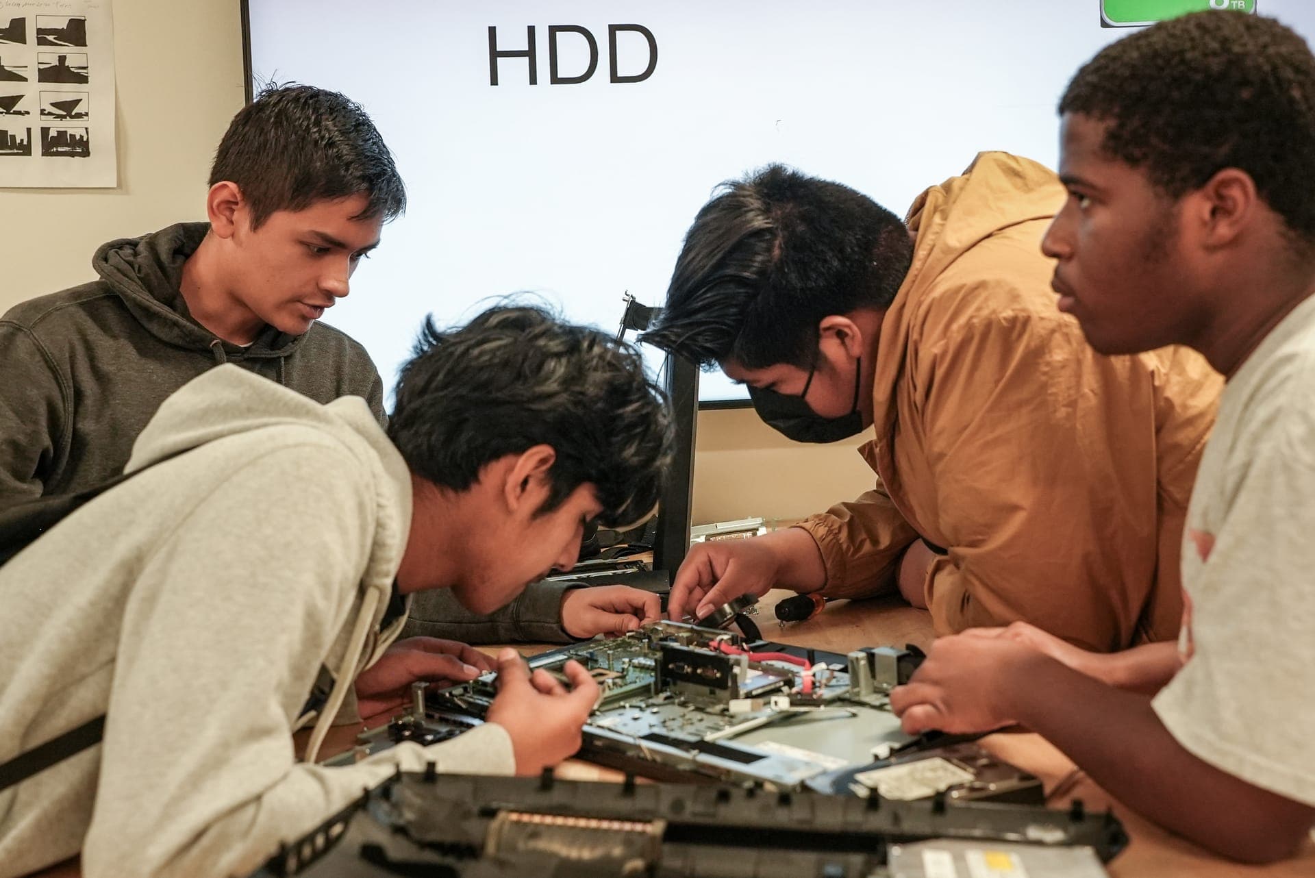 Students disassembling a laptop in a hands-on technology class