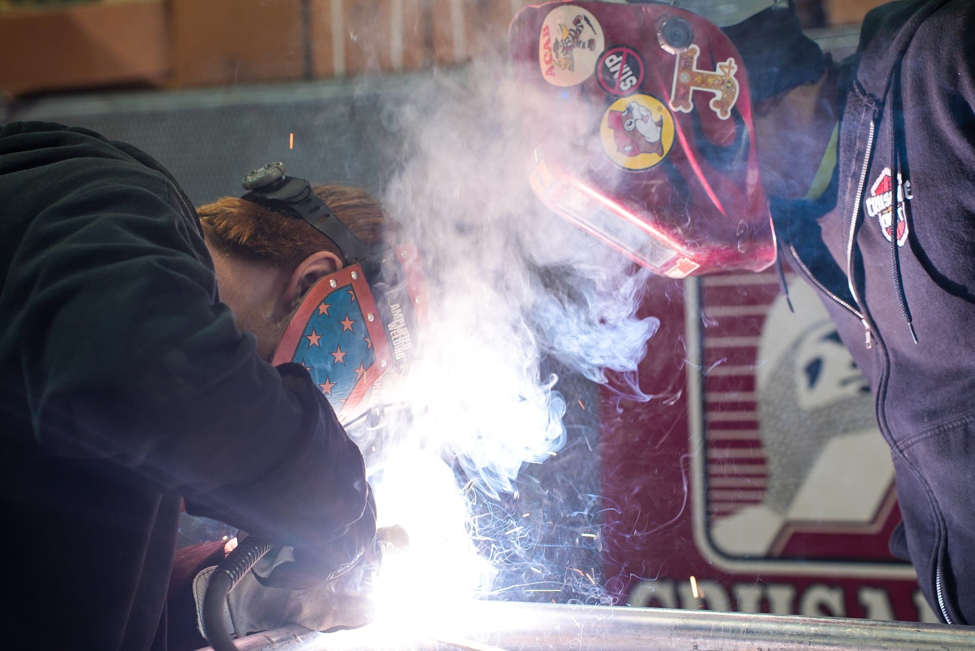A student welding with sparks flying in a fabrication shop